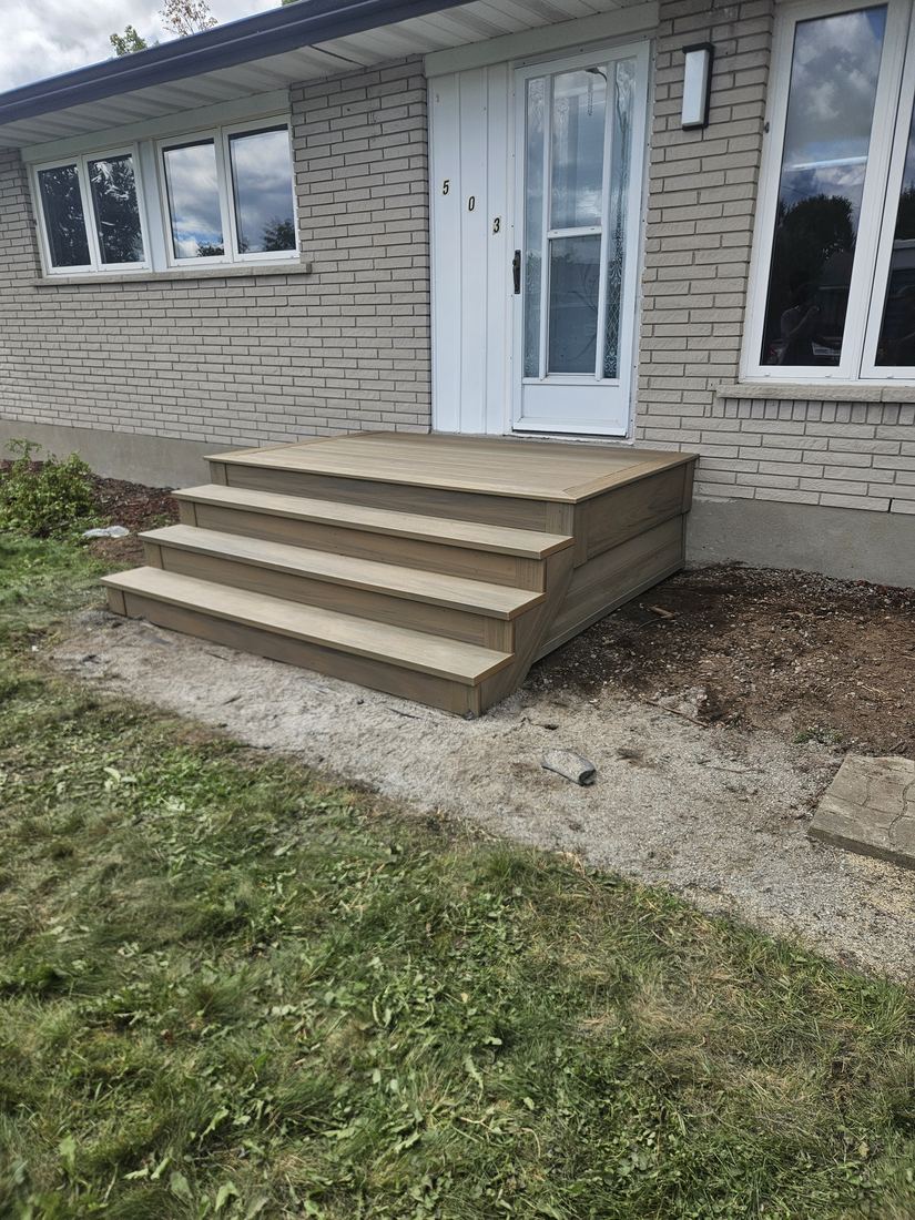 Small beige composite entry deck with three steps in front of a brick house door
