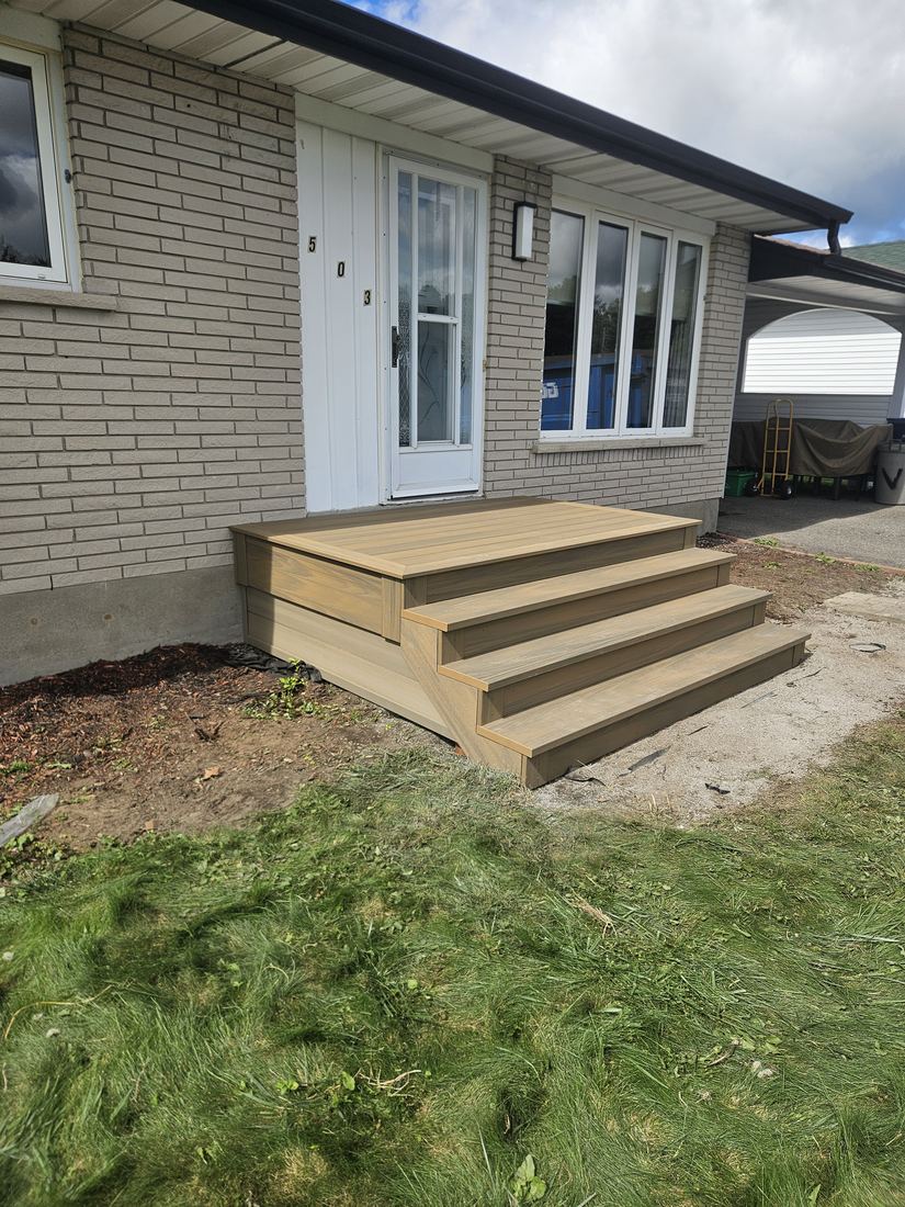 Side view of a beige composite front landing and steps on a brick house