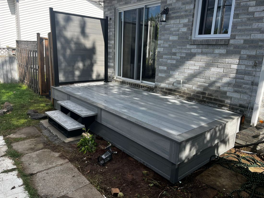 Low grey composite deck with side steps and a privacy screen, angled view