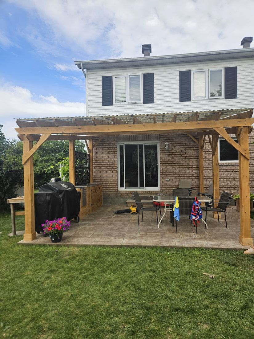 Cedar pergola with translucent roof over a stamped concrete patio, outdoor kitchen and dining area