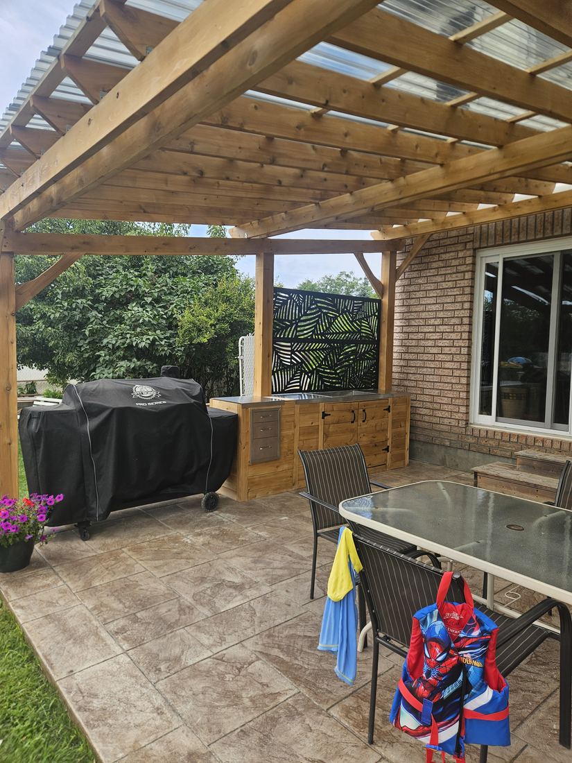 Under the cedar pergola: stamped concrete patio, outdoor kitchen and leaf-pattern privacy panel