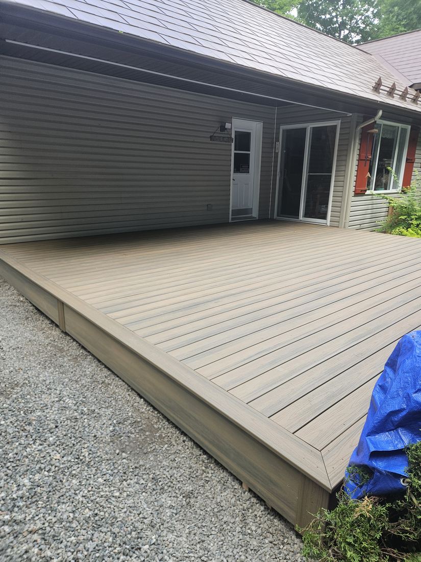 Large ground-level composite deck in grey-brown, built against a house with grey siding