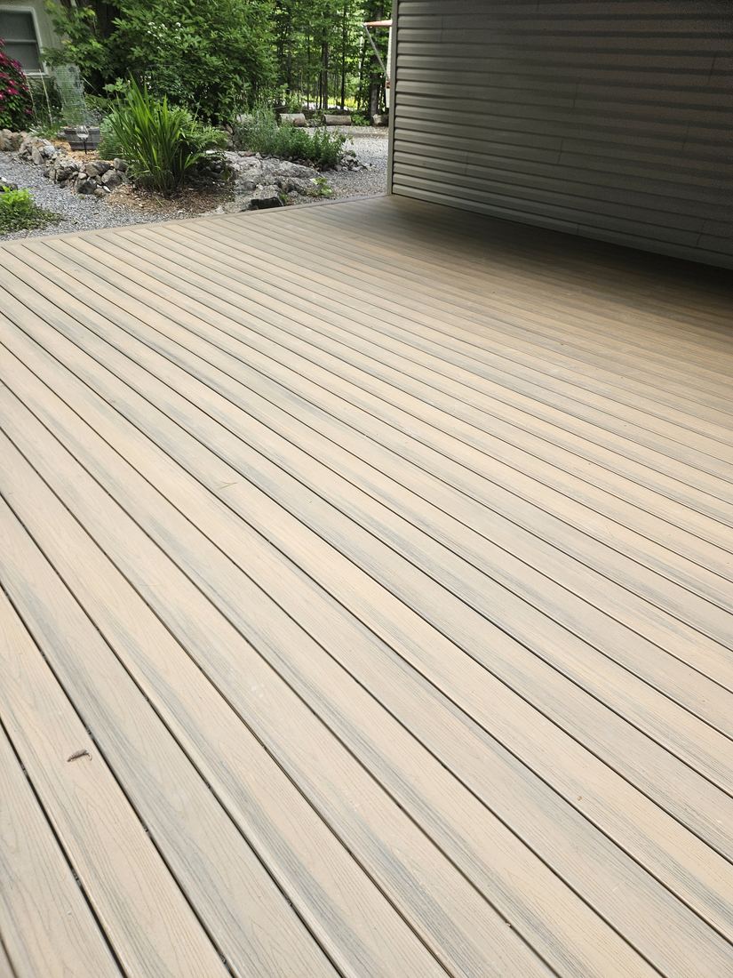 Close view of beige-grey composite decking boards laid along the house siding