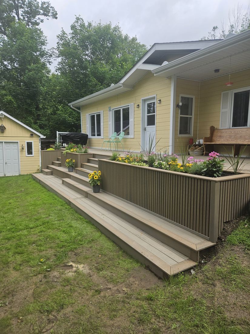 Angled view of composite steps and slatted planter wall, with a shed in the background