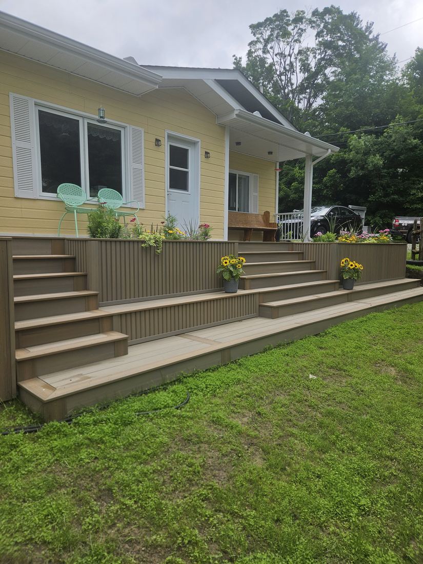 Two-level composite deck with side staircase and planters clad in vertical slats