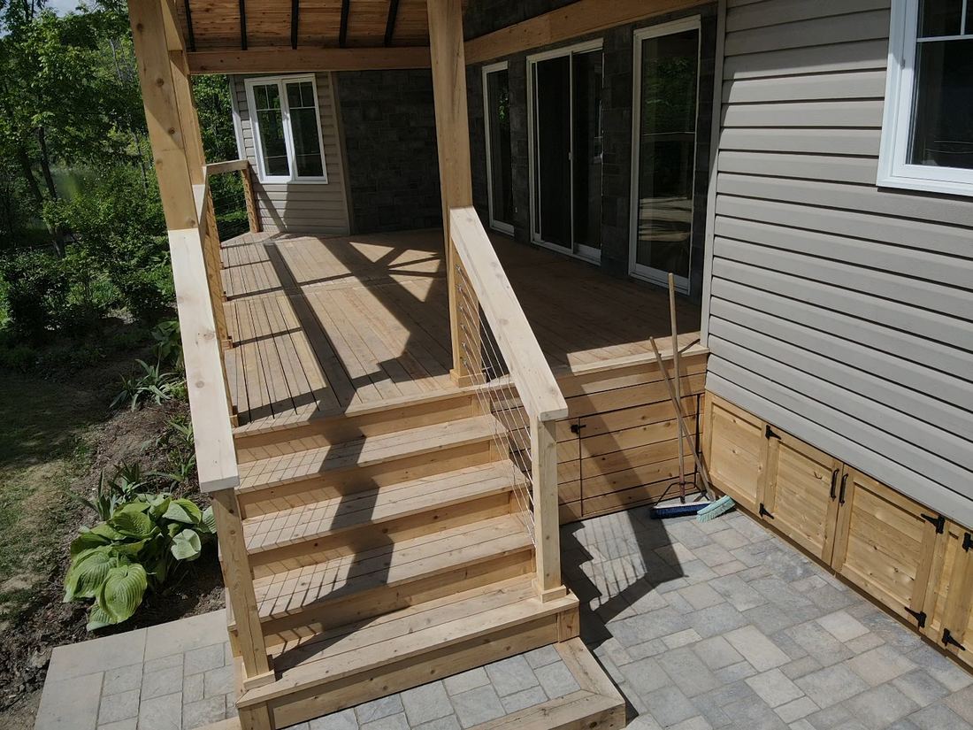 Cedar stairs with cable railing up to the deck, and storage doors beneath it