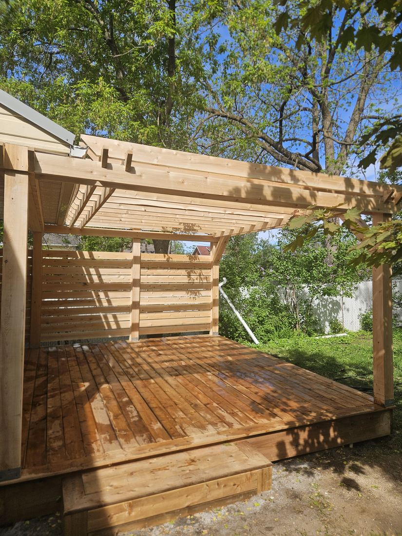 Wood pergola and deck with slatted privacy screen, access step and trees in the background