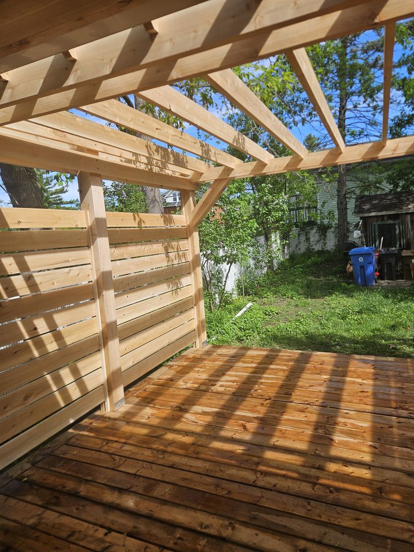 Pressure-treated wood pergola with horizontal-slat privacy screen over a freshly built deck
