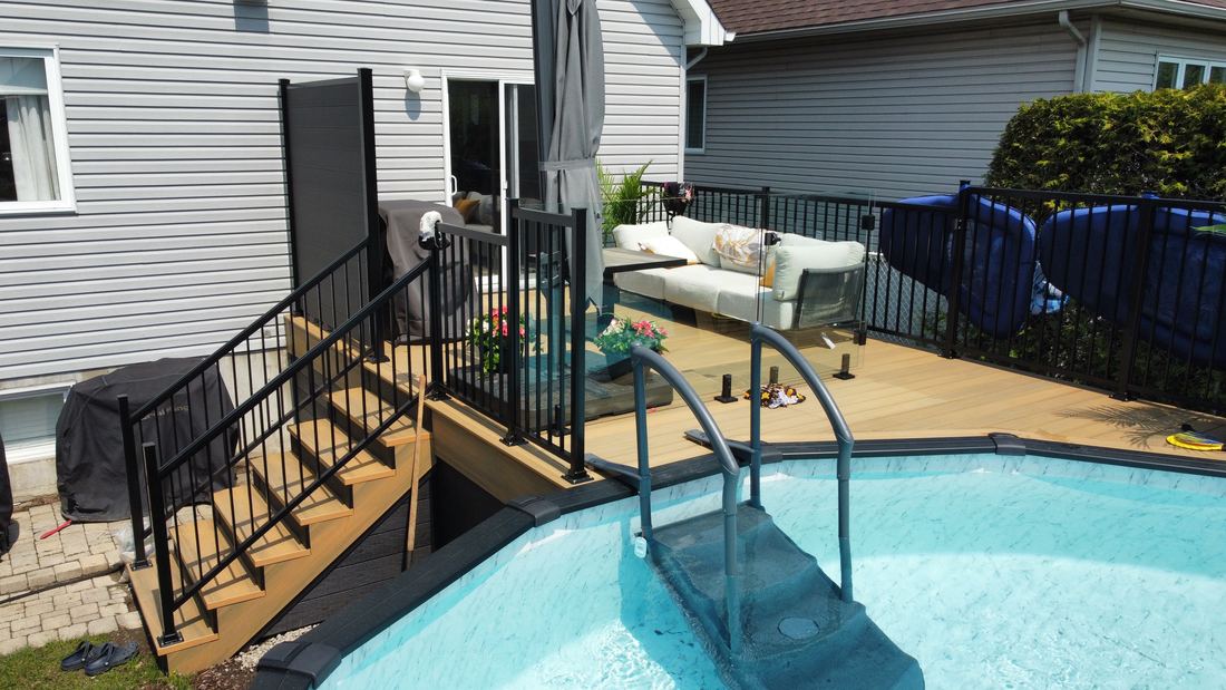 Composite deck by the pool, view of the stairs with black railing and privacy screen