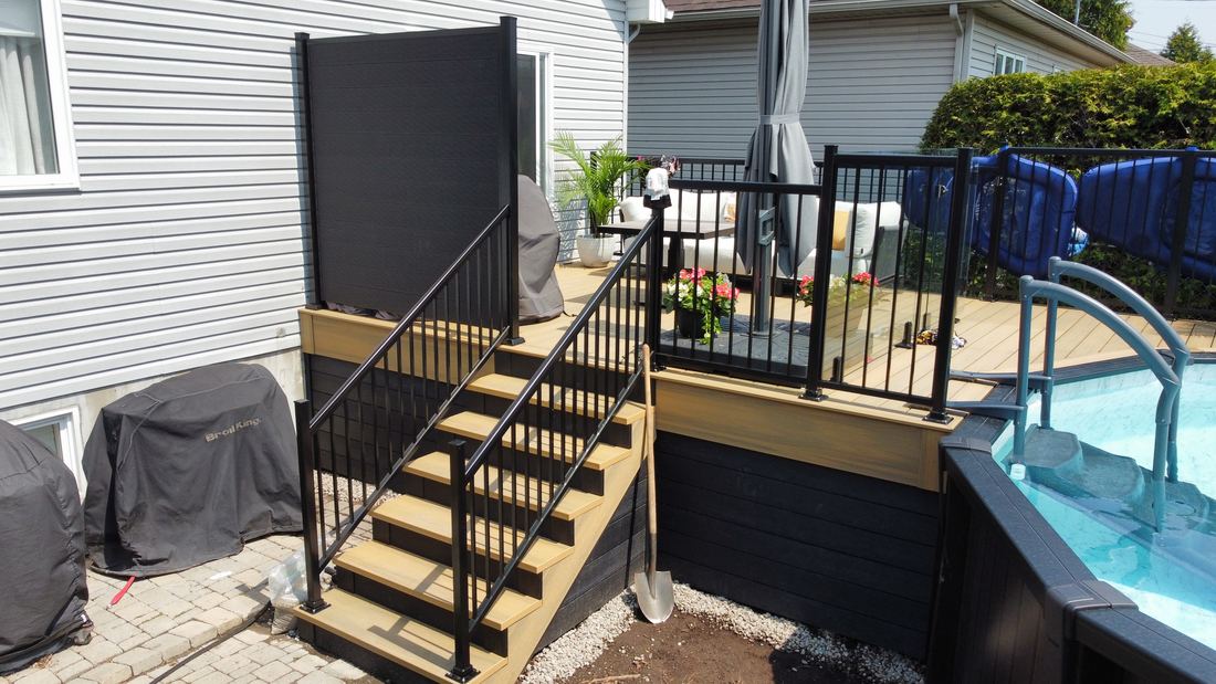 Composite stairs with black railing leading up to the deck, with privacy screen and dark skirting