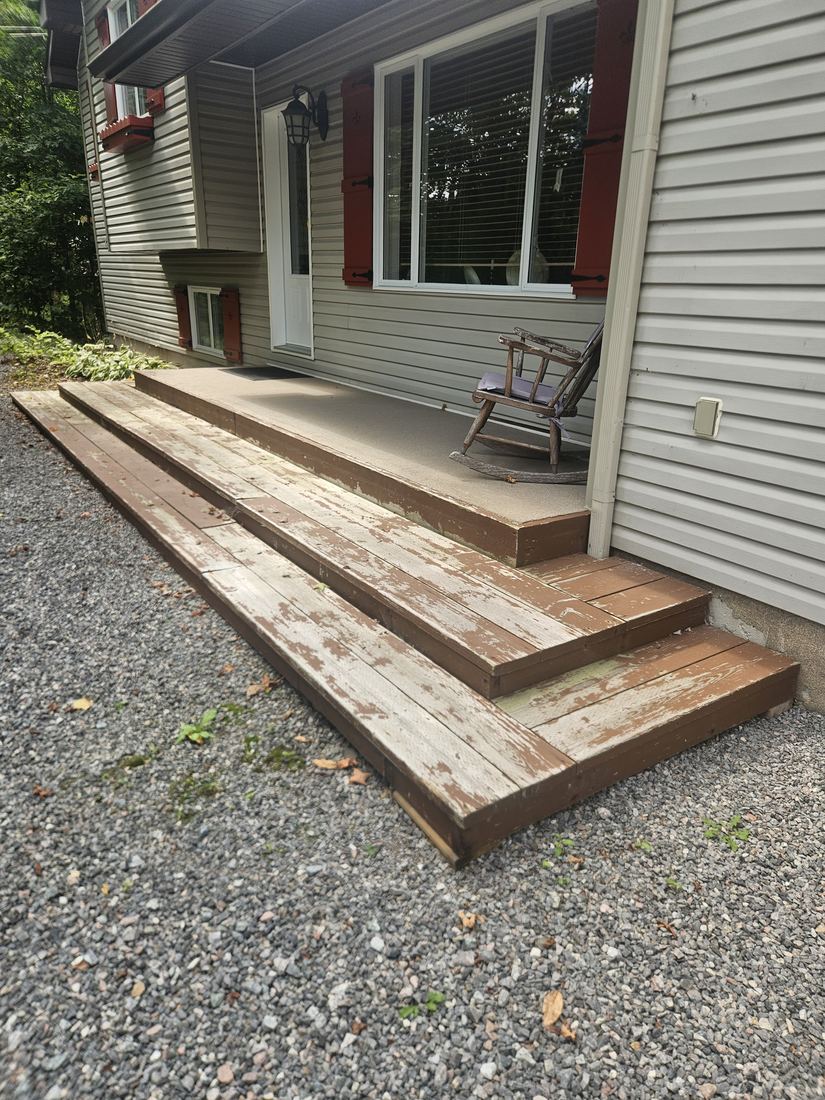 Worn wood steps and landing with peeling paint at a front entrance, before renovation