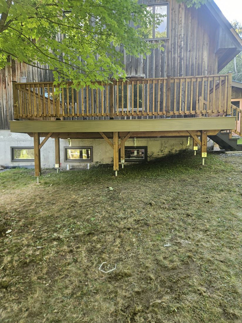 Raised deck on posts with wood railing, view of the structure from below