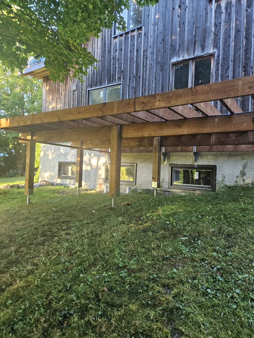 Pressure-treated wood frame of a raised deck, beams and posts on anchored footings