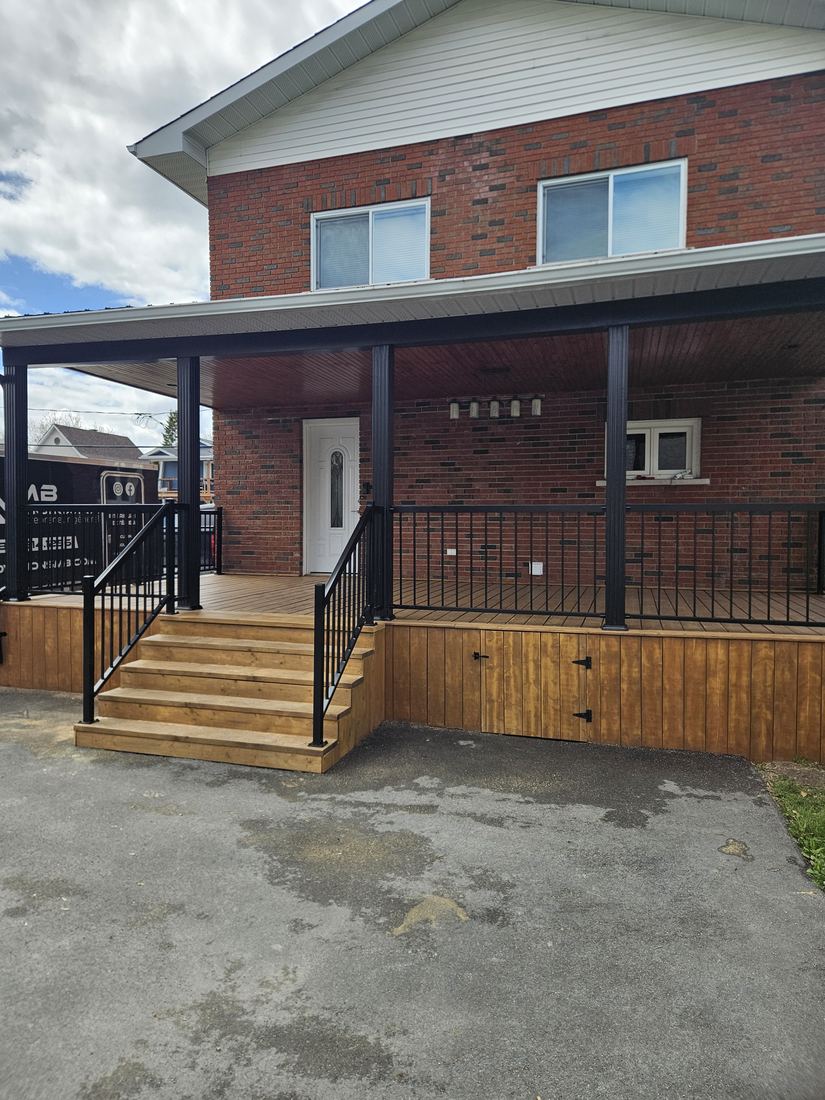 Covered porch and stairs with an access door under the platform and black railing