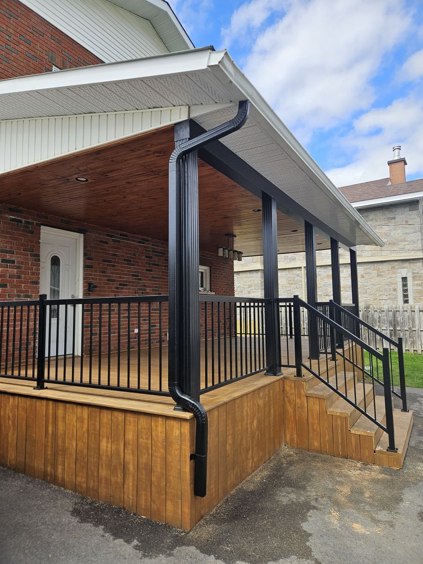 Porch detail: wood ceiling, black column, railing and pressure-treated wood entry steps