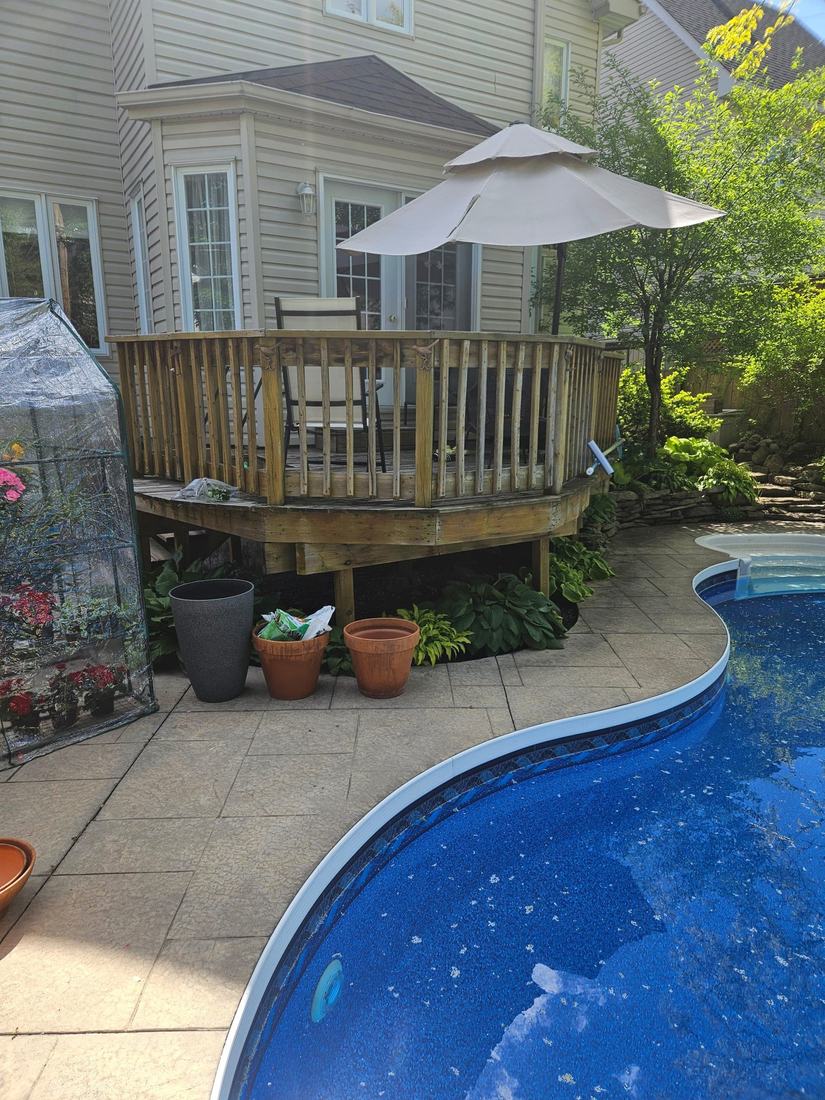 Older wood deck with wooden baluster railing next to a pool, before renovation
