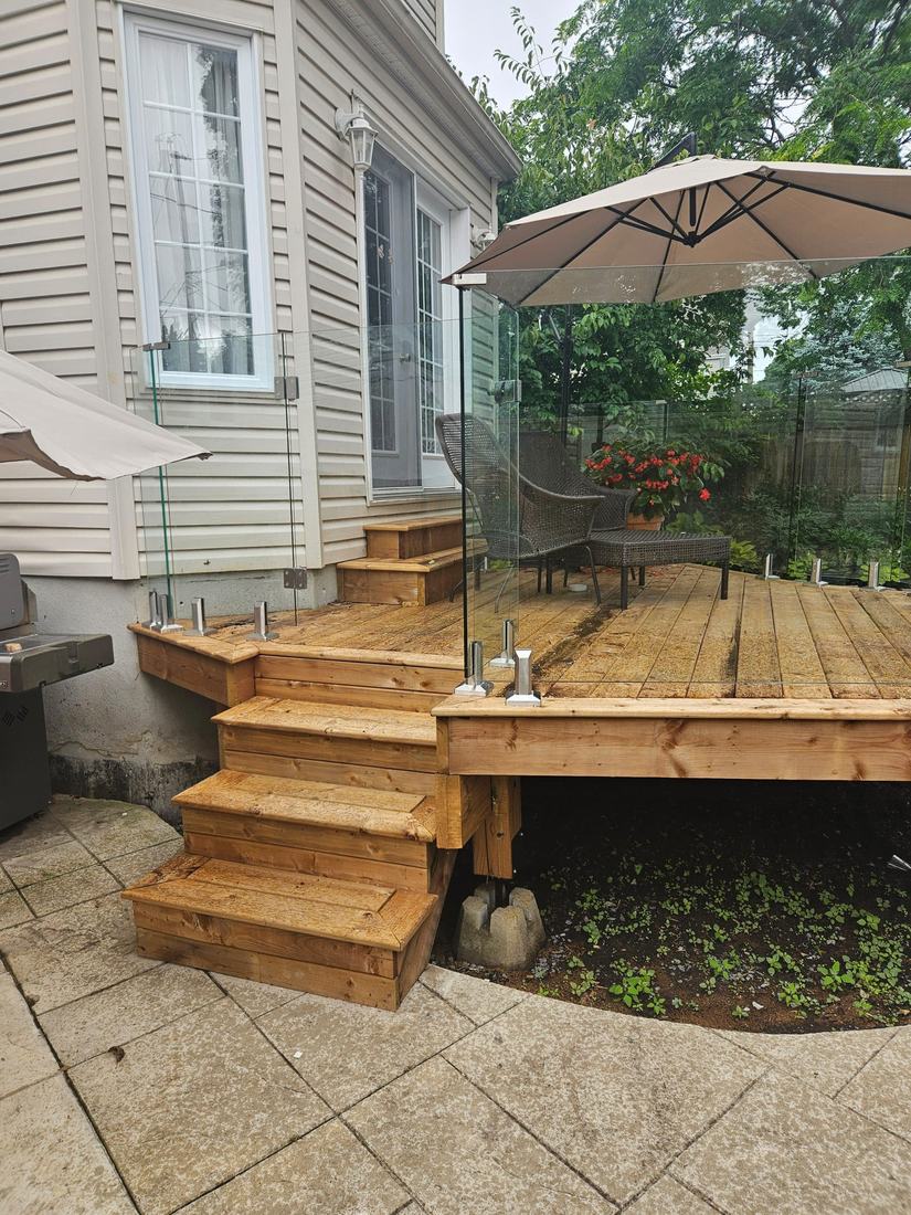 View of the pressure-treated wood stairs and stainless-post glass railing on a new deck