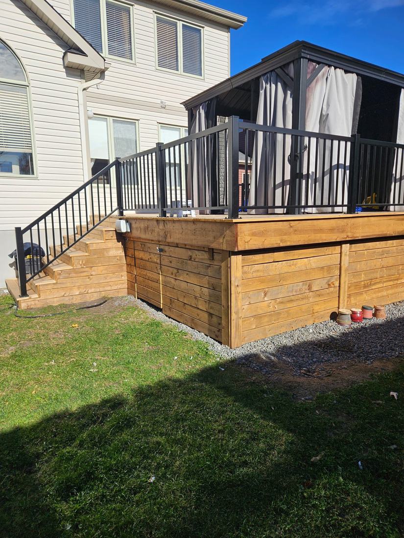 Raised pressure-treated wood deck with stairs, black aluminum railing and wood skirting below