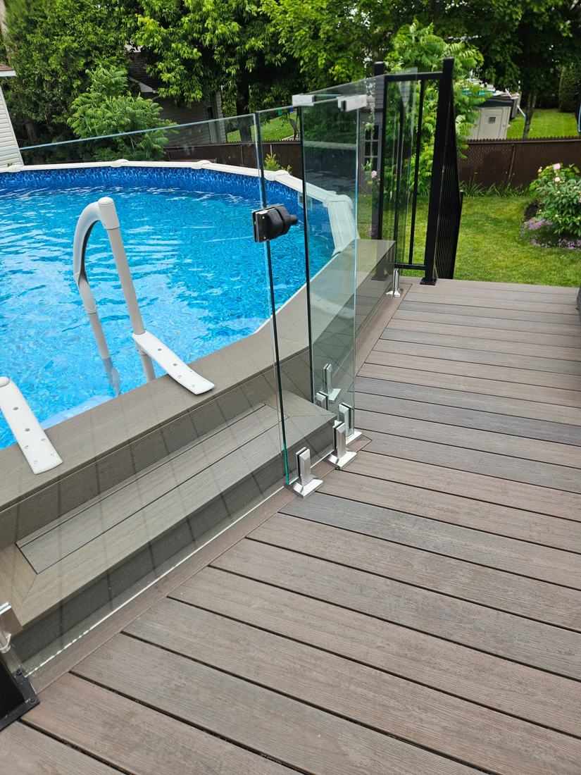 Detail of a glass gate with latch beside an above-ground pool, on a grey-brown composite deck
