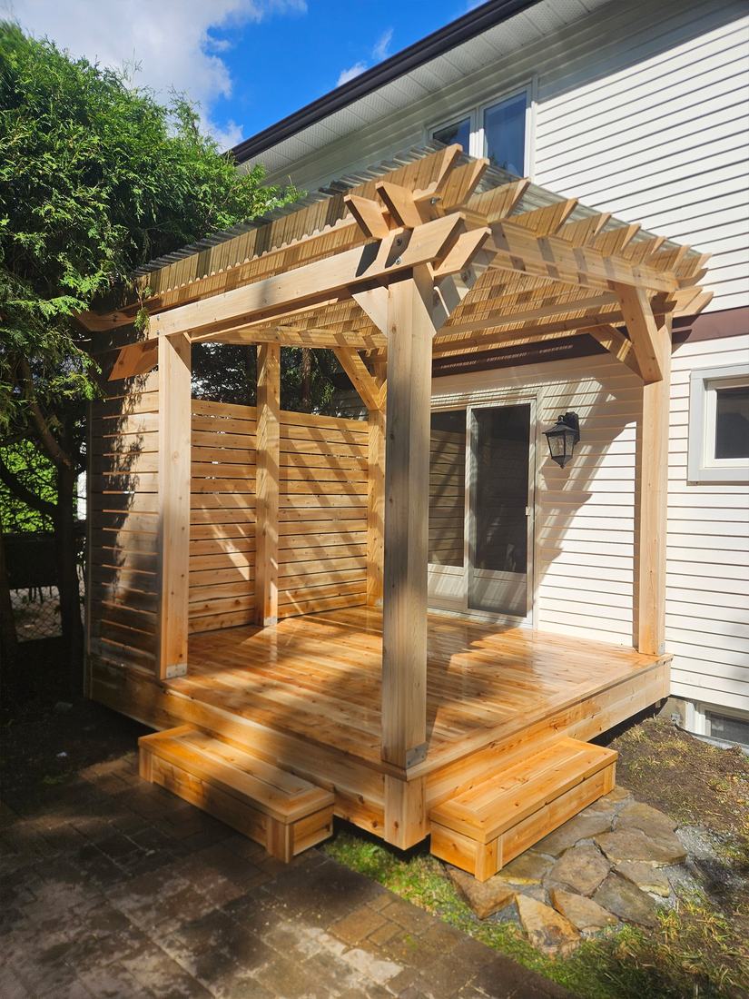 Small cedar deck with pergola, slatted privacy walls and two steps, built against a house
