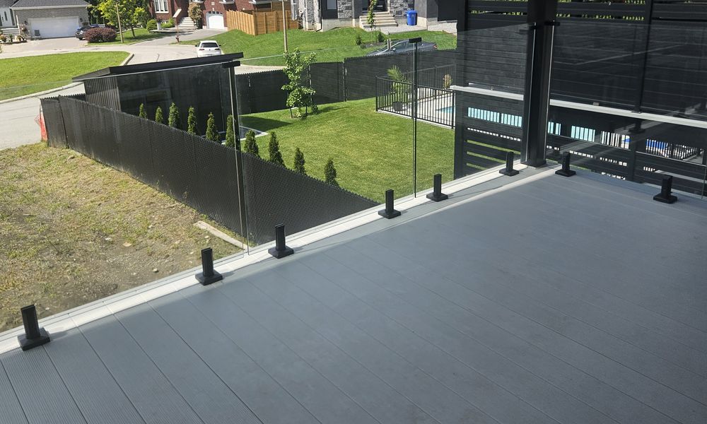 Glass railing on a grey composite deck overlooking the yard