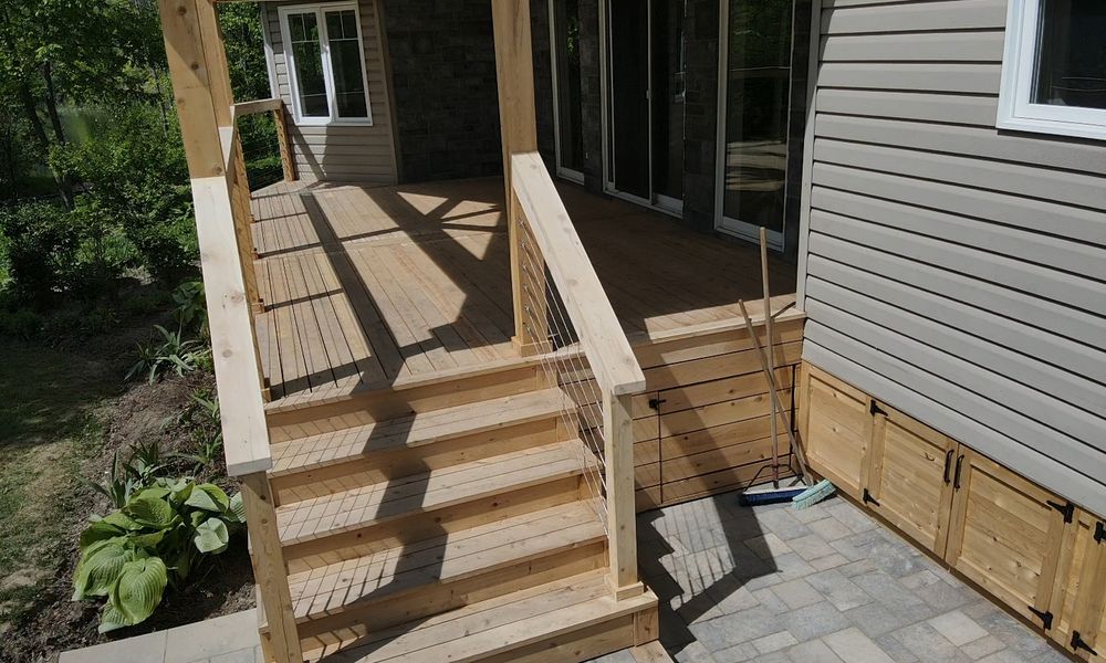 Wooden deck and stairs under a covered porch, with cable railings