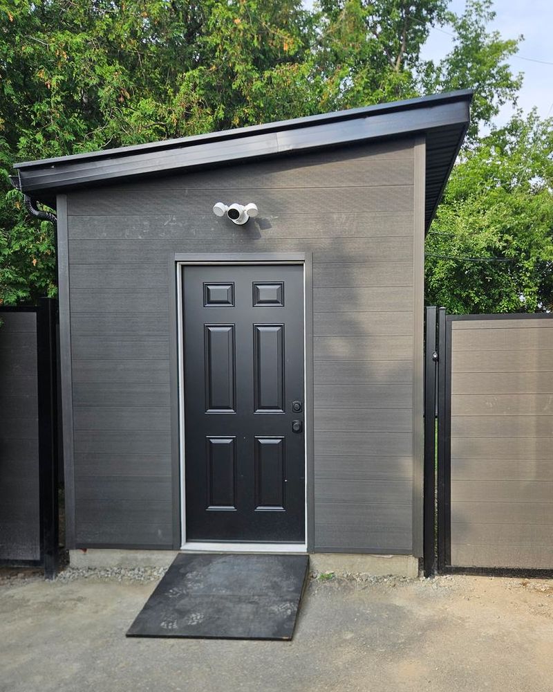 Dark grey shed with a single-slope roof and a black door