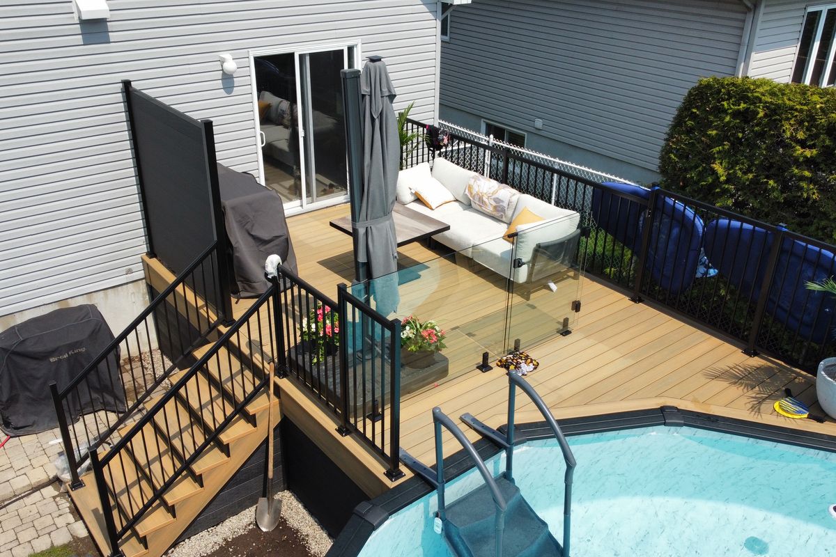 Pool deck with black aluminum railings, glass and a privacy panel